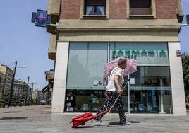 Una mujer se protege con un paraguas ante los 35 grados que marcaban estos termómetros al mediodía.
