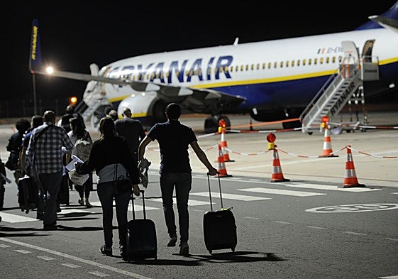 Pasajeros se disponen a subir a un avion de Ryanair con sus equipajes de mano.