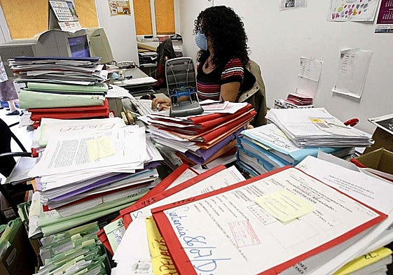 Una funcionaria trabaja rodeada de montañas de papeles en Elche.