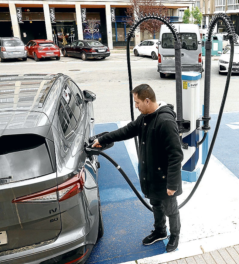 Un hombre recarga su vehículo eléctrico en una estación