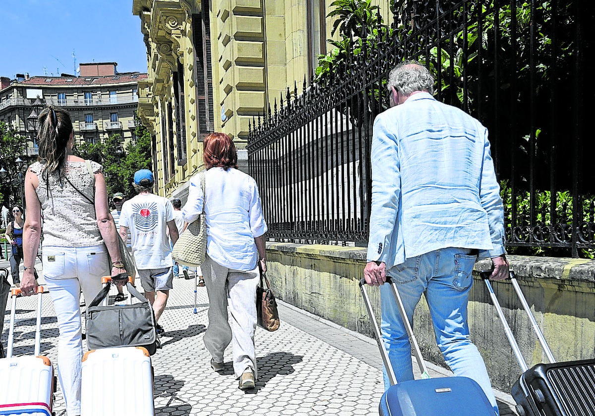 Dos turistas arrandan sendas maletas por una calle del centro de San Sebastián