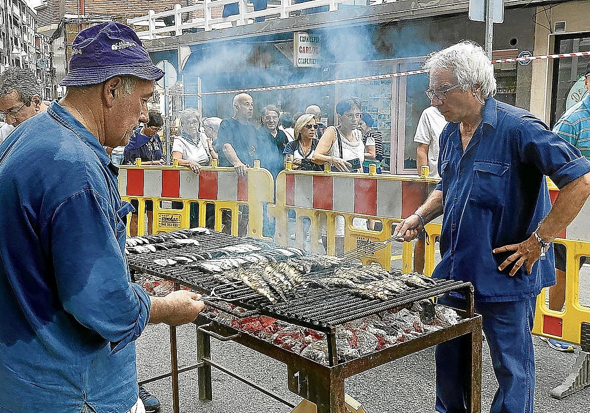 Jesús María Salazar, a la izquierda, lleva medio siglo asando sardinas en las fiestas.