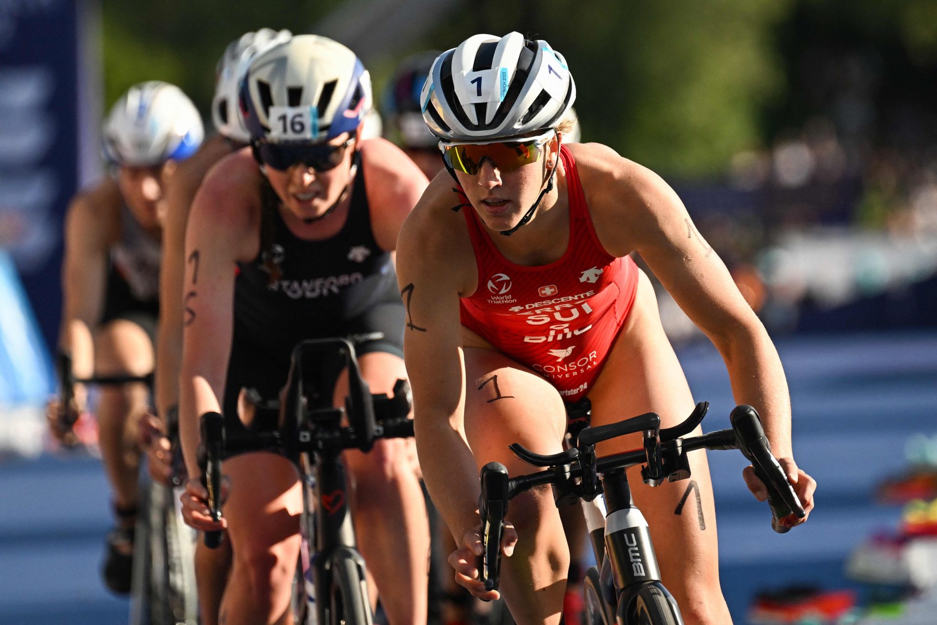 La deportista suiza rueda con su bicicleta por delante de Non Stanford en el triatlón de Múnich de 2022.