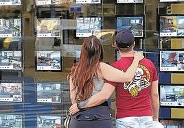 Una pareja joven contempla ofertas de viviendas a la venta.