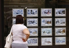 Una mujer observa los anuncios en el escaparate de una agencia inmobiliaria.