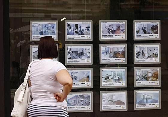 Una mujer observa los anuncios en el escaparate de una agencia inmobiliaria.