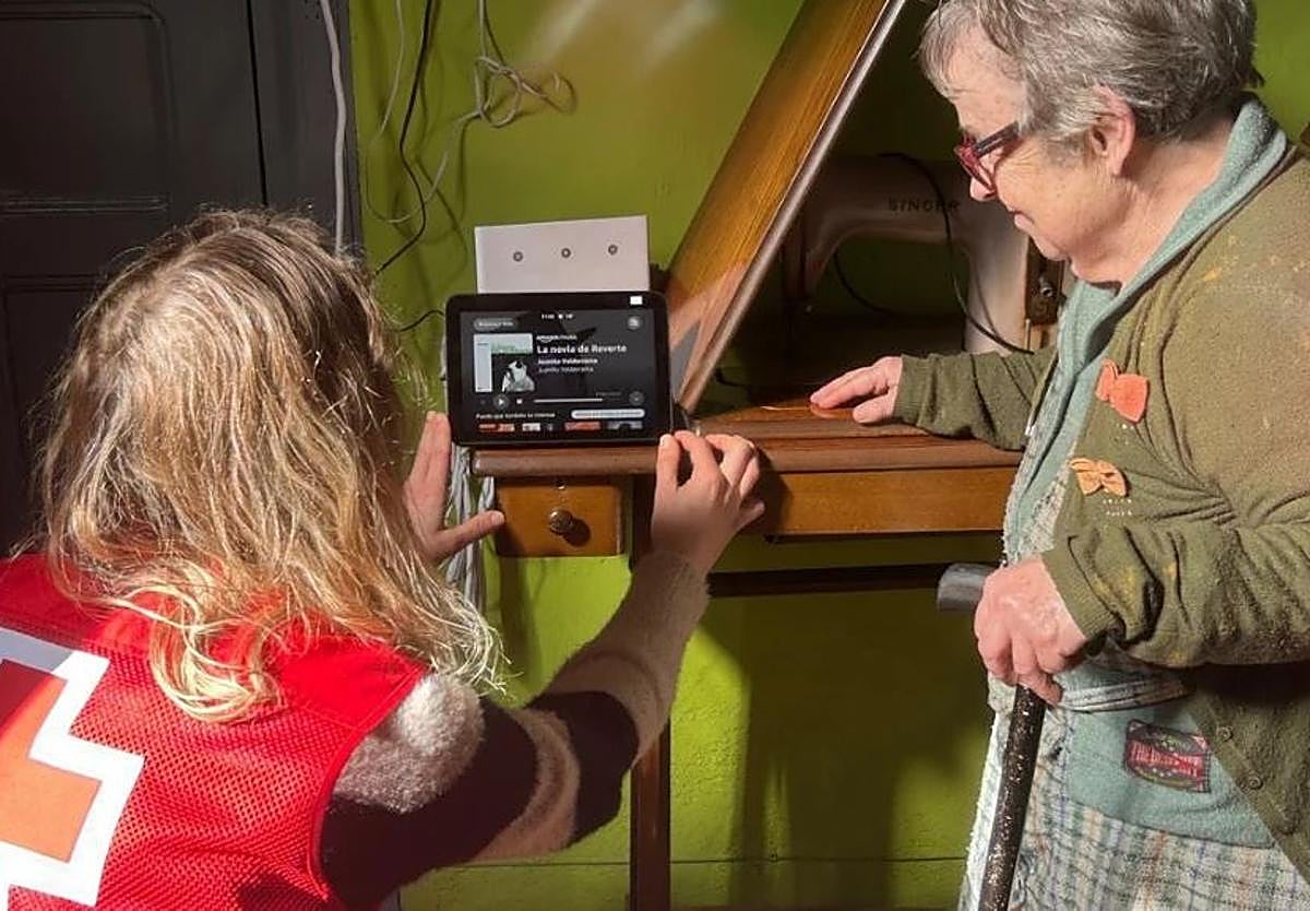 Una voluntaria de Cruz Roja ayuda a una persona mayor participante en el programa Voces en red