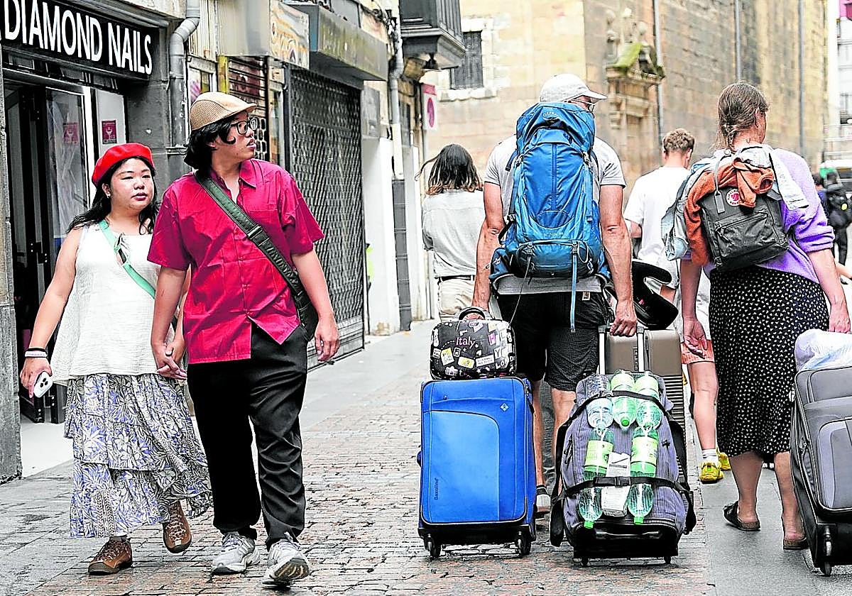 En el Casco Viejo. Turistas acarrean sus maletas por la zona histórica de Bilbao durante la calurosa jornada de ayer.