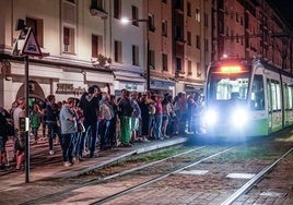 Usuarios del tranvía esperan la llegada del convoy durante una noche de fiestas de Vitoria.