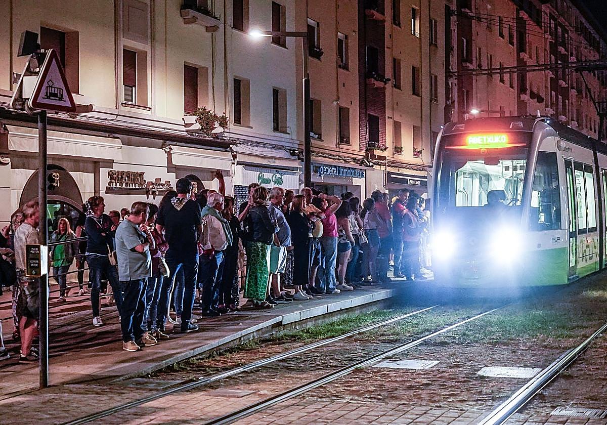 Usuarios del tranvía esperan la llegada del convoy durante una noche de fiestas de Vitoria.