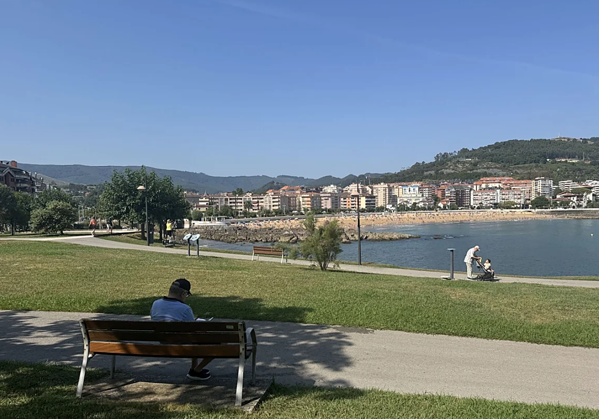 Un hombre lee sentado en un banco del parque de Cotolino de Castro Urdiales,