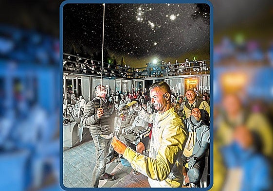 Juanje Valdelana orienta el láser hacia el cielo estrellado de Elciego (donde brillan las Tres Marías del cinturón de Orión en este fotomontaje) mientras su hijo Juan explica uno de los vinos servidos en la premiada cata estelar de Bodegas Valdelana.