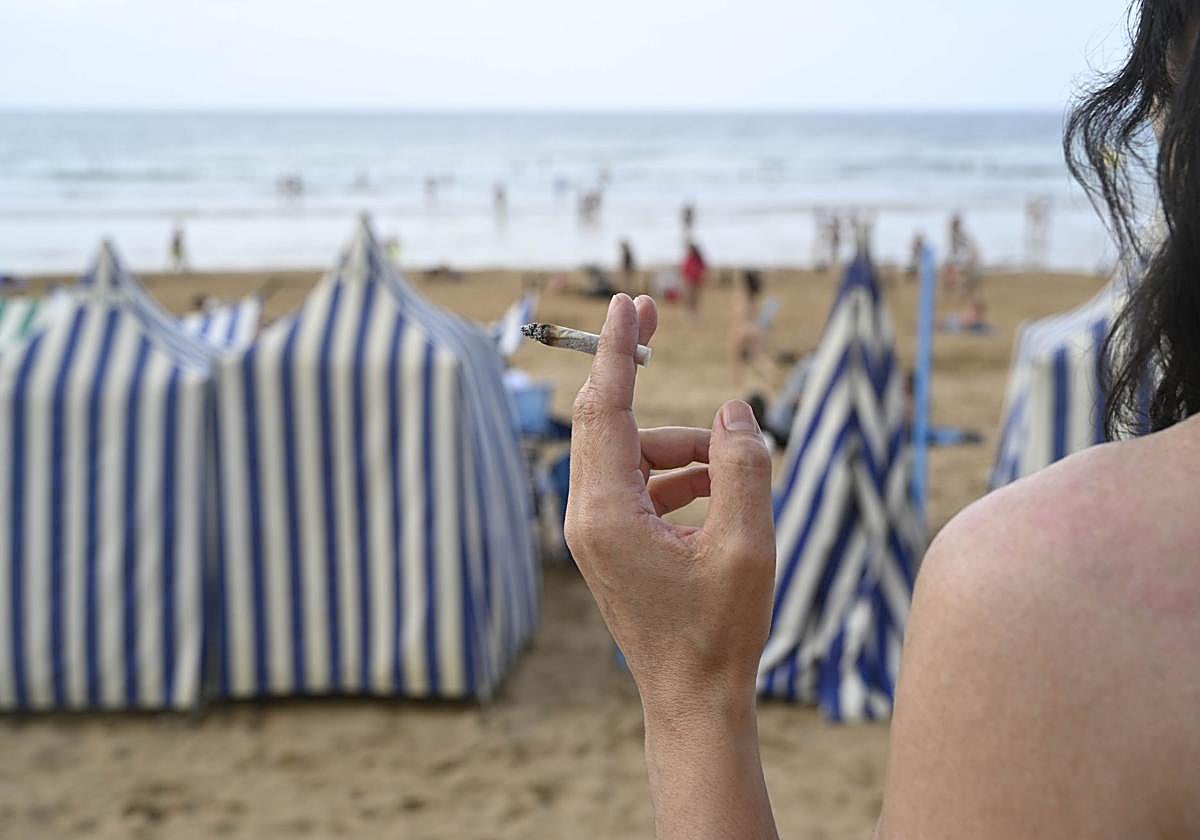 Una mujer fuma un cigarro en la playa de Zarautz, una práctica que estará prohibida dede el próximo verano.