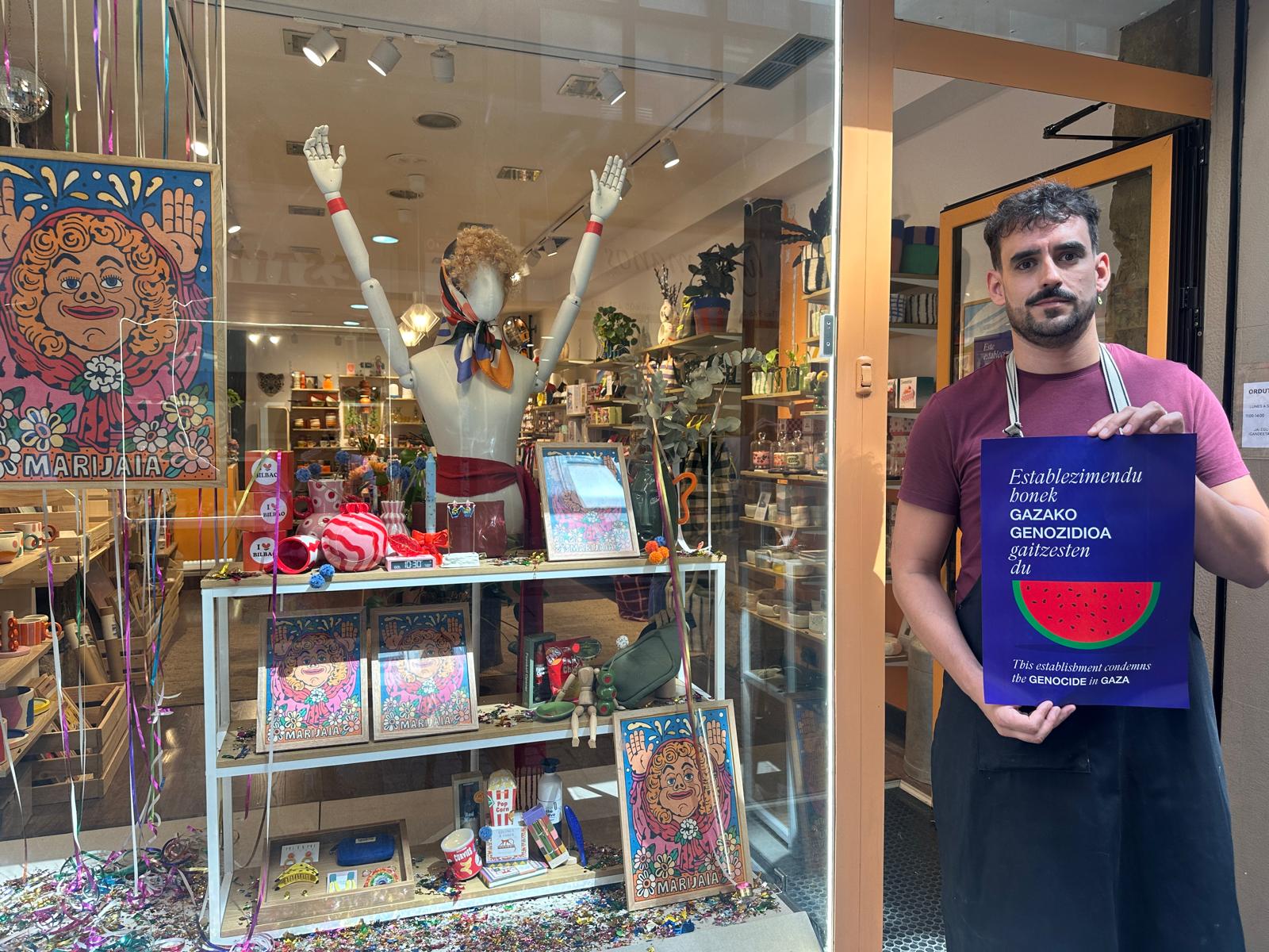 Ander Lantarón posa con el cartel en apoyo a Palestina en la puerta de su comercio de El Casco Viejo.