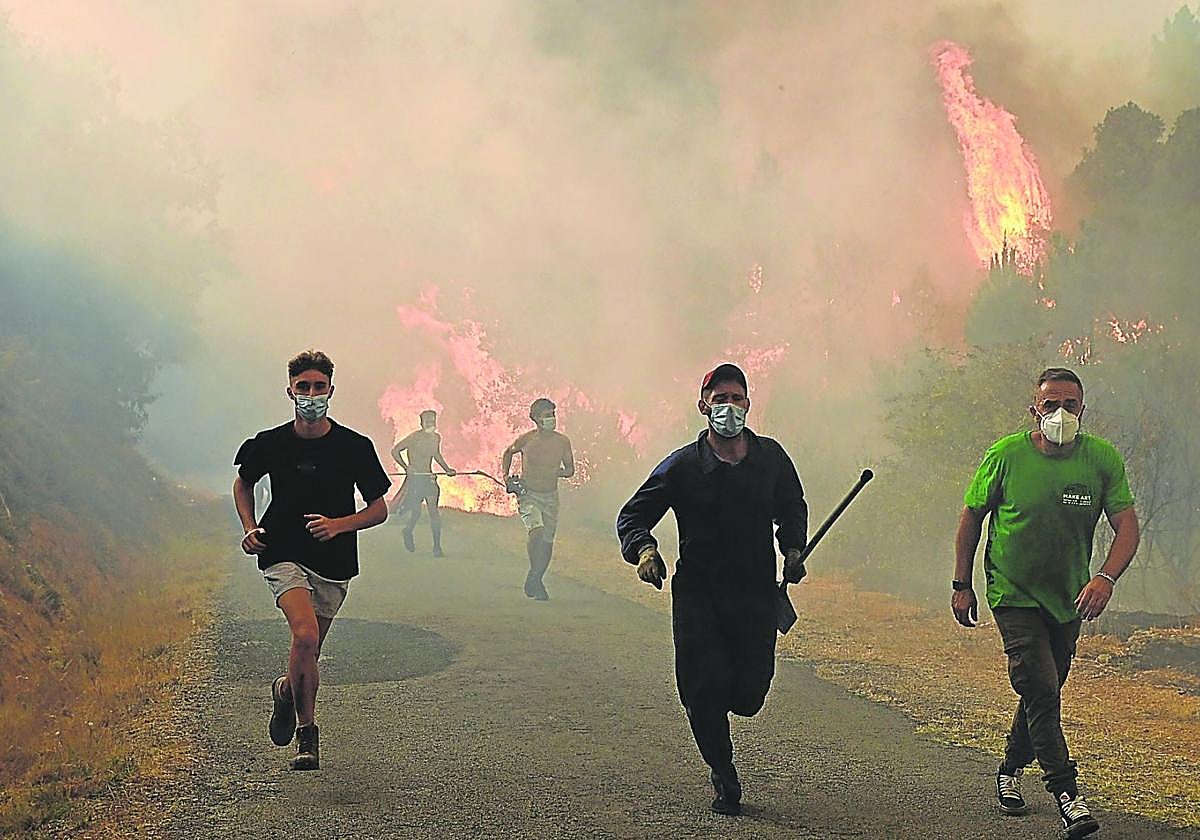 Asediados. Granjeros huyen del avance incontenible de las llamas que se extienden por Larouco, en Ourense.