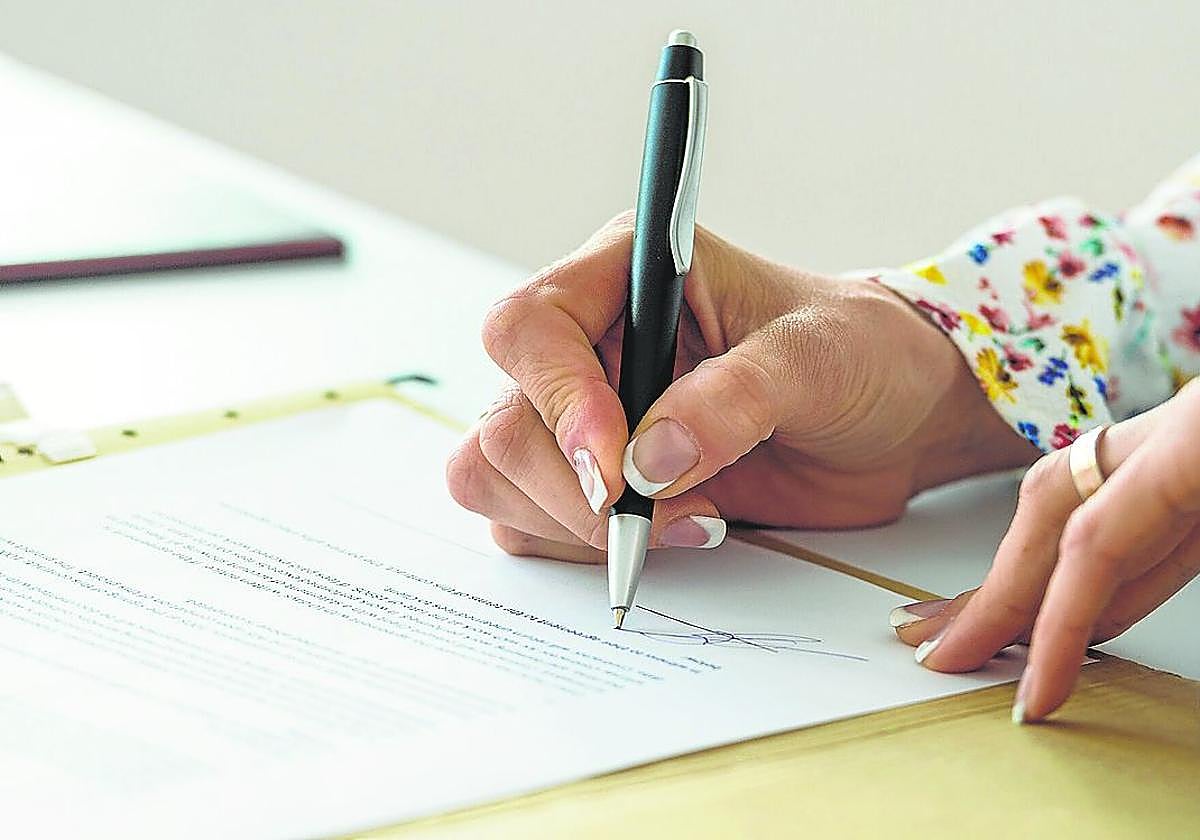 Una mujer firma un documento notarial.