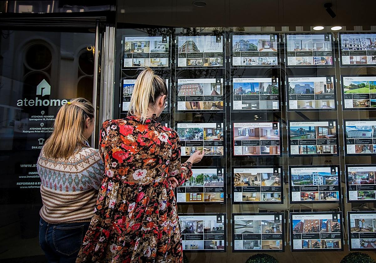 Dos mujeres observan el escaparate de una inmobiliaria