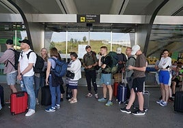 Varios pasajeros esperan a la llegada de autobuses en las inmediaciones del aeropuerto de Loiu en Bilbao.