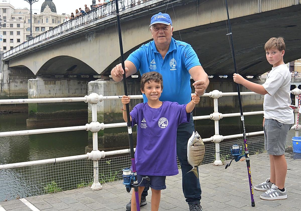 Urko, de seis años, posa con la primera captura del día con su monitor, José Luis.