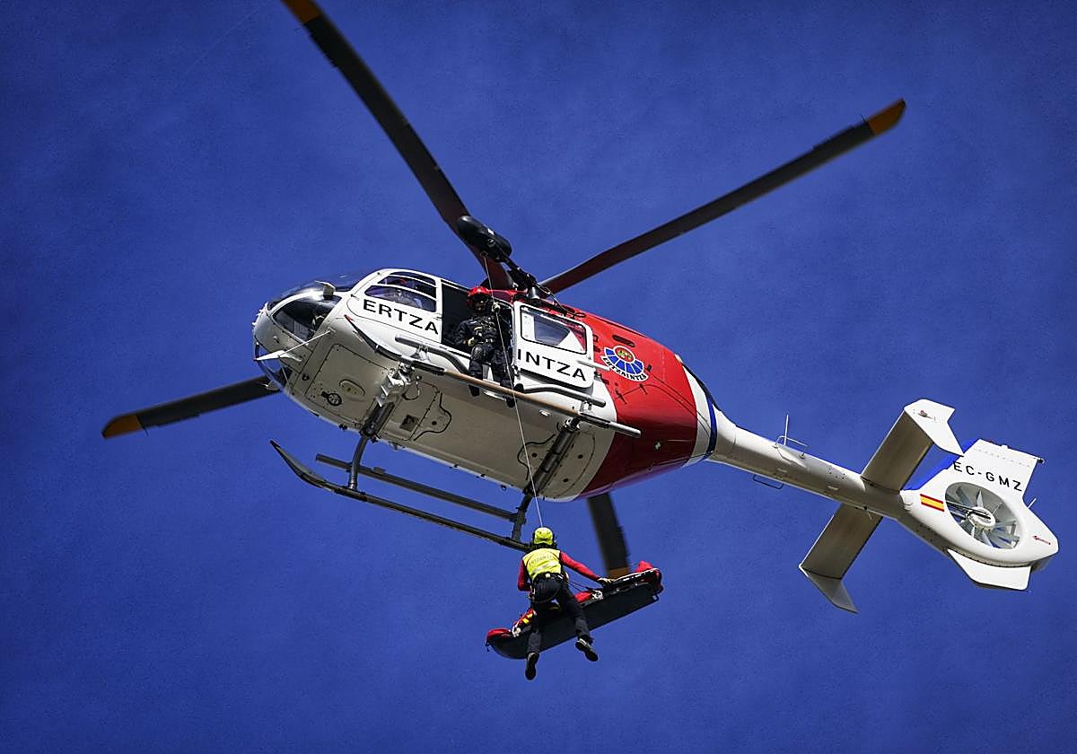 Un helicóptero de la Ertzaintza iza a una persona rescatada.