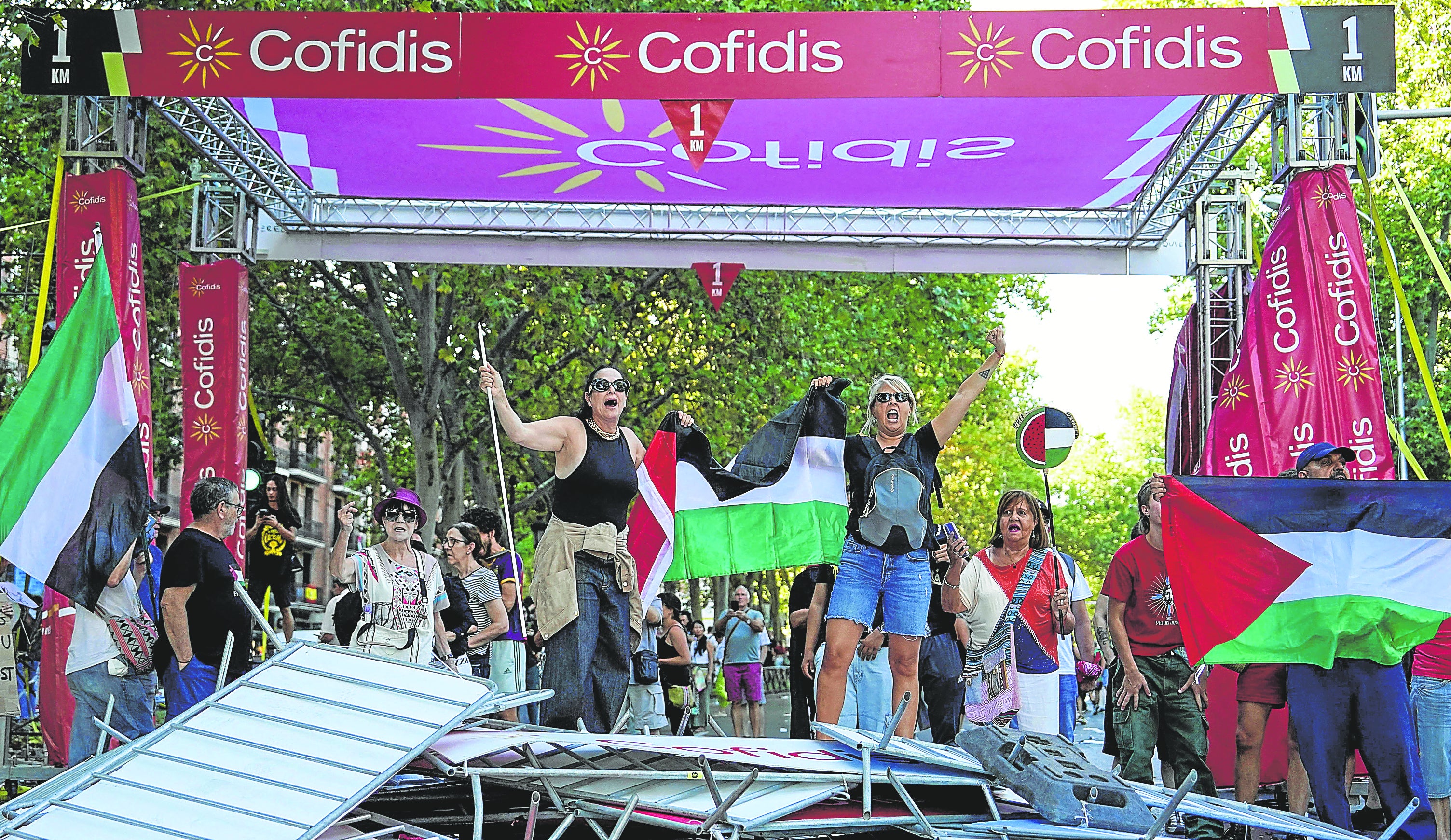 En el recorrido dos manifestantes con la bandera de Palestina protestan en el paso de un kilómetro para la meta.