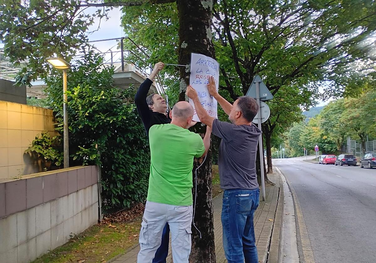 Varios representantes del grupo ecologista Sagarrak colocan un cartel contra la tala de árboles en Abaroa, que no seguirá adelante.