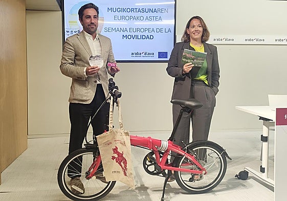 Jon Nogales, diputado de Movilidad Sostenible y Patricia Pérez, directora de Movilidad y Transportes posan junto a la bicicleta plegable, valorada en 500 euros, que recibirá la alavesa que más uso el transporte público el año pasado