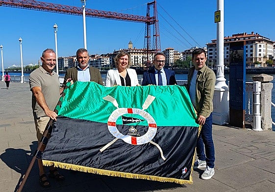 Representantes institucionales, patrocinadores y miembros del club de remo de Portugalete, con la bandera frente al Puente Colgante.