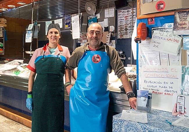 Los dueños de la pescadería Carlos, junto a la recogida de firmas.
