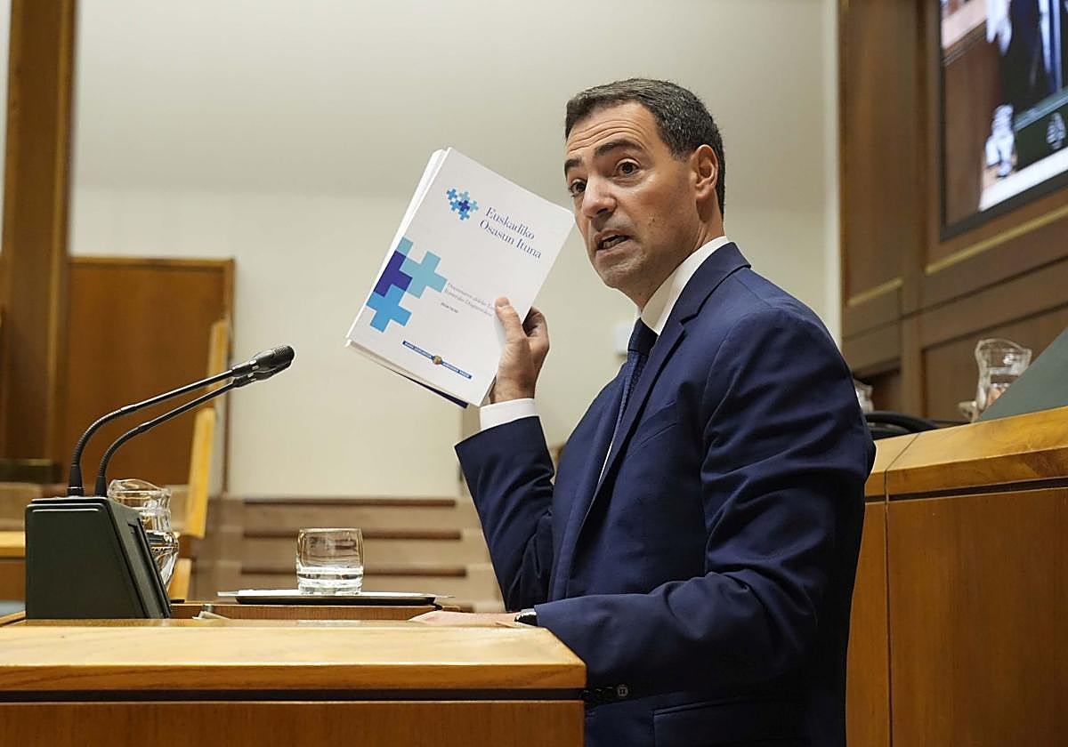 El lehendakari, Imanol Pradales, muestra el documento del Pacto de Salud en la tribuna.