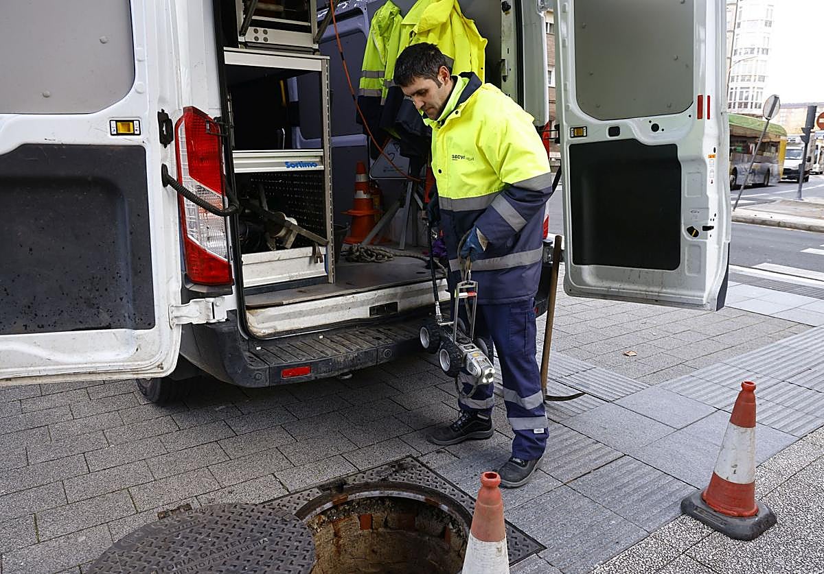 Dos operarios se disponen a realizar tareas de mantenimiento en el alcantarillado.
