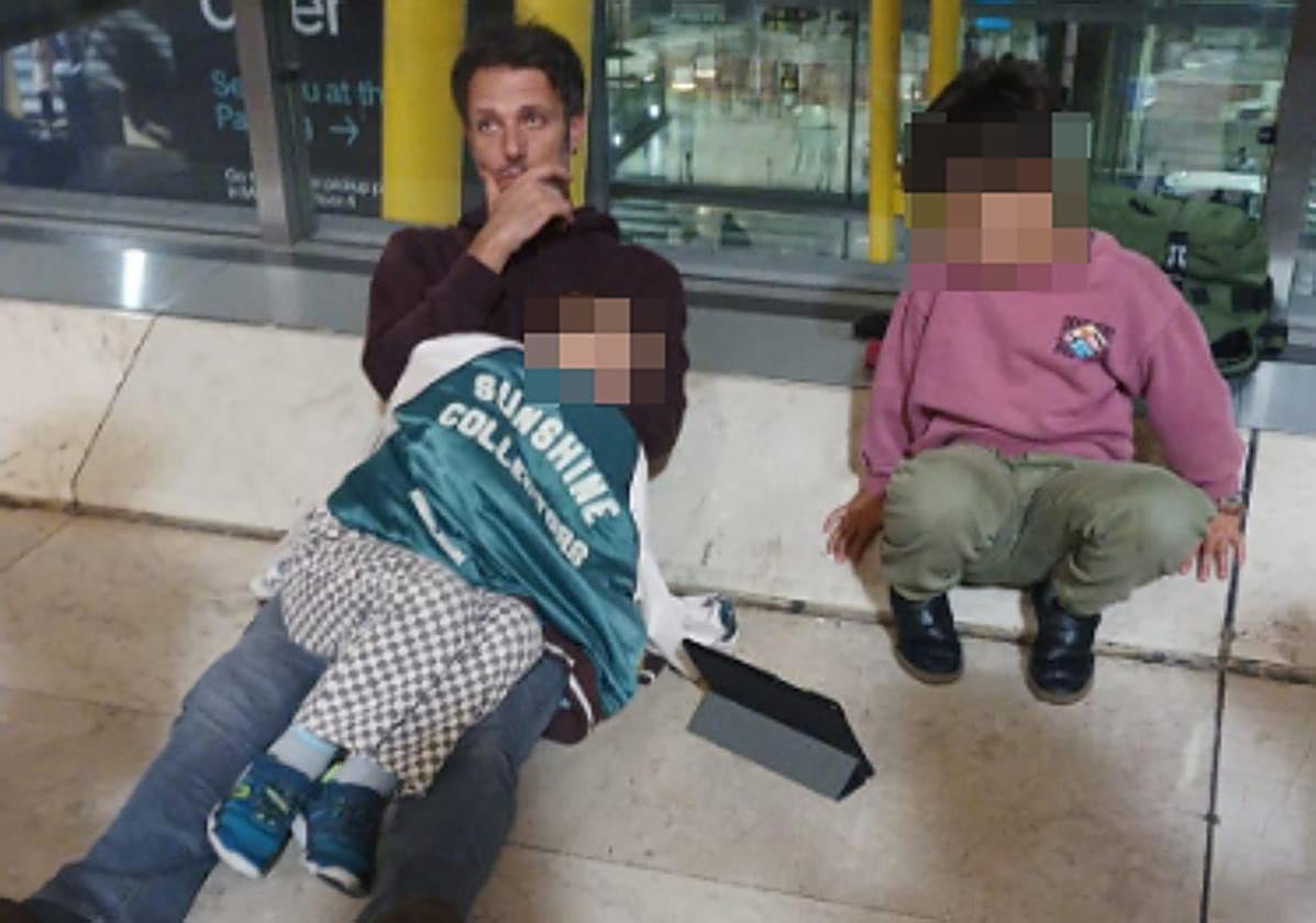 Un padre trata de dormir a uno de sus pequeños, en el suelo de Barajas.