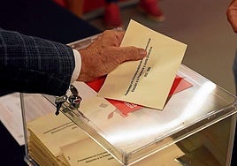 Una persona se dispone a introducir su voto en la urna.