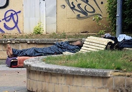 Un hombre duerme con sus posesiones en el abandonado parque de Paseo de la Senda, junto a las vías del tren.