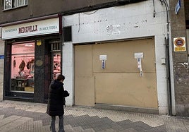 Una mujer observa los paneles que cubran la lonja recuperada por la Policía Local en la calle Nicaragua.