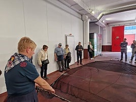 La redera Ana Rosa Ispizua explica en la cofradía de Bermeo las partes de una red a un grupo de turistas.
