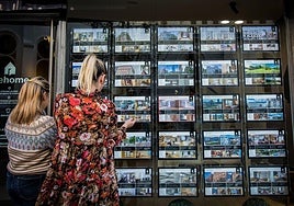 Dos mujeres observan el escaparate de una inmobiliaria.