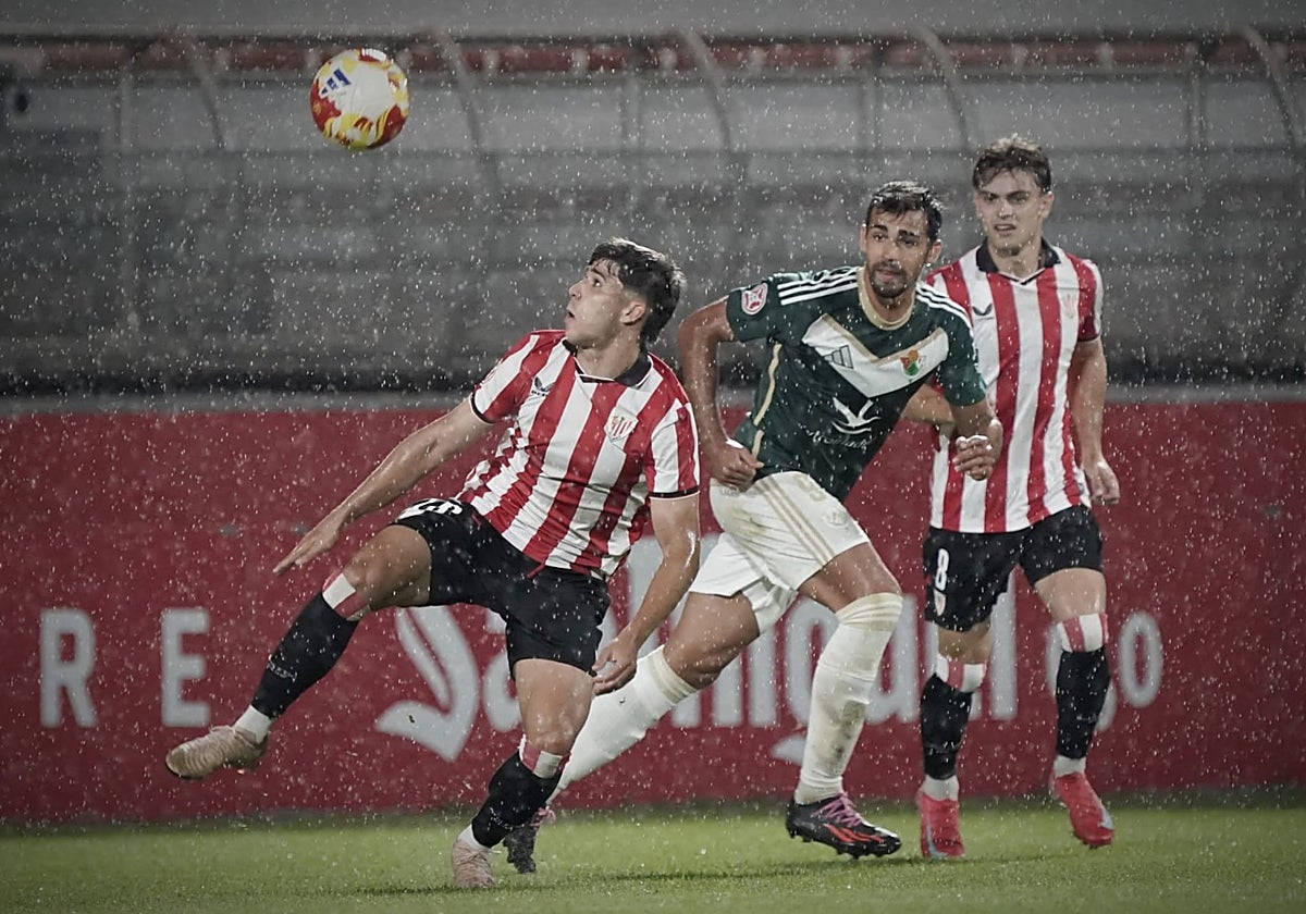Eder García y Eñaut Lete rodean a Diego Gómez en un lluvioso partido.