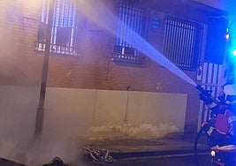 Un bombero apaga el incendio de un contenedor.