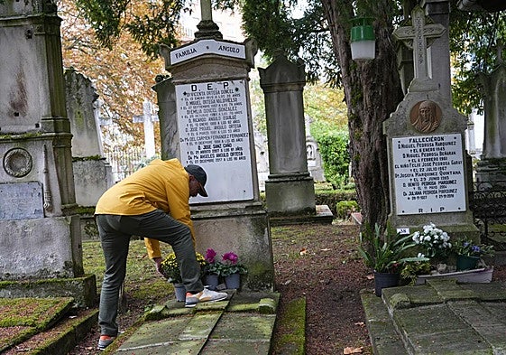 Una persona deposita flores en una sepultura del cementerio de Santa Isabel.