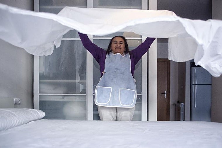 Una trabajadora del hogar hace la cama en la vivienda en que trabaja.