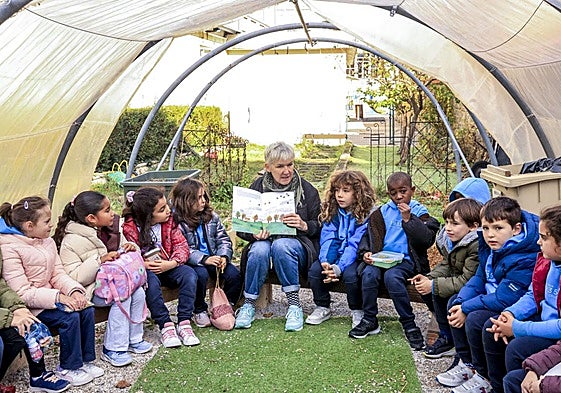 Alumnos de 2º de Primaria del colegio Vera Cruz atienden la lectura de una historia en inglés en el huerto del colegio.