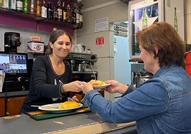 Elizane le sirve un pintxo de tortilla a una de sus clientas en el bar Zuloa.