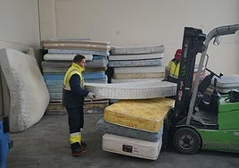 Un operario separa colchones en una planta de reciclaje