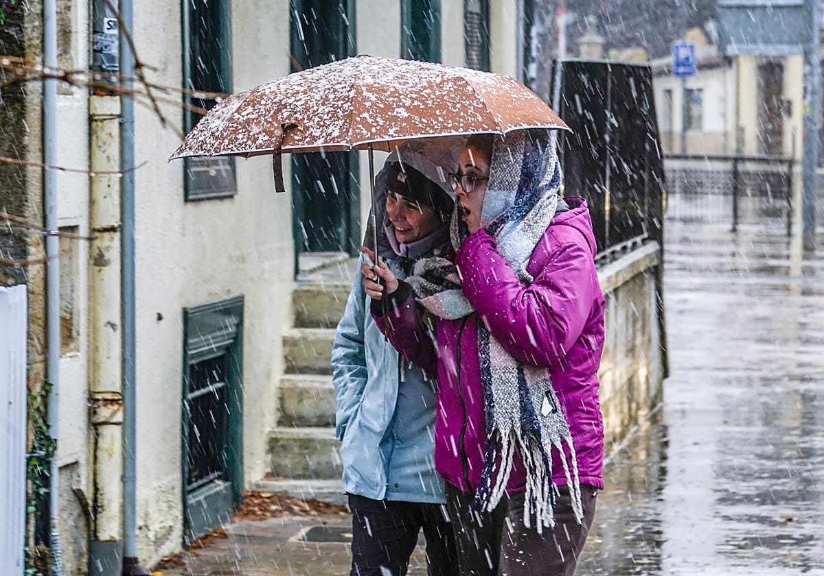 Dos chicas se protegen de la nieve en Murguía.