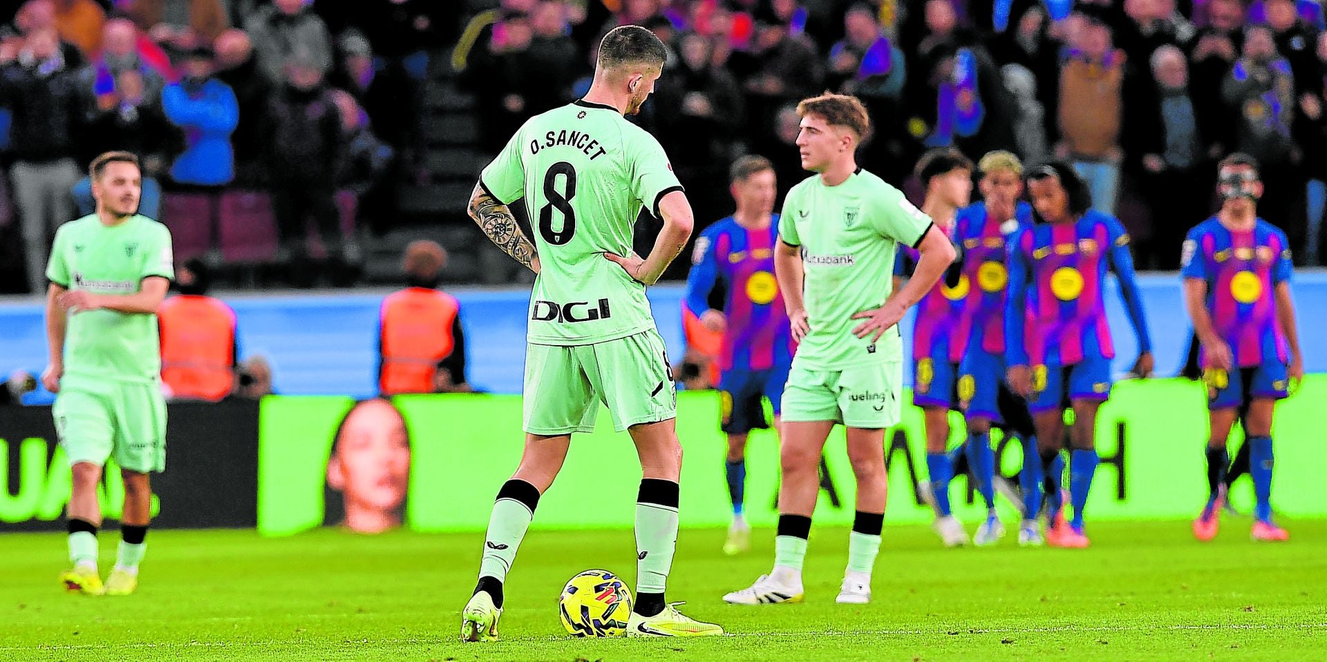 Sancet y Jauregizar, cabizbajos en el centro del campo mientras los jugadores del Barça celebran uno de los cuatro goles en el partido del sábado.