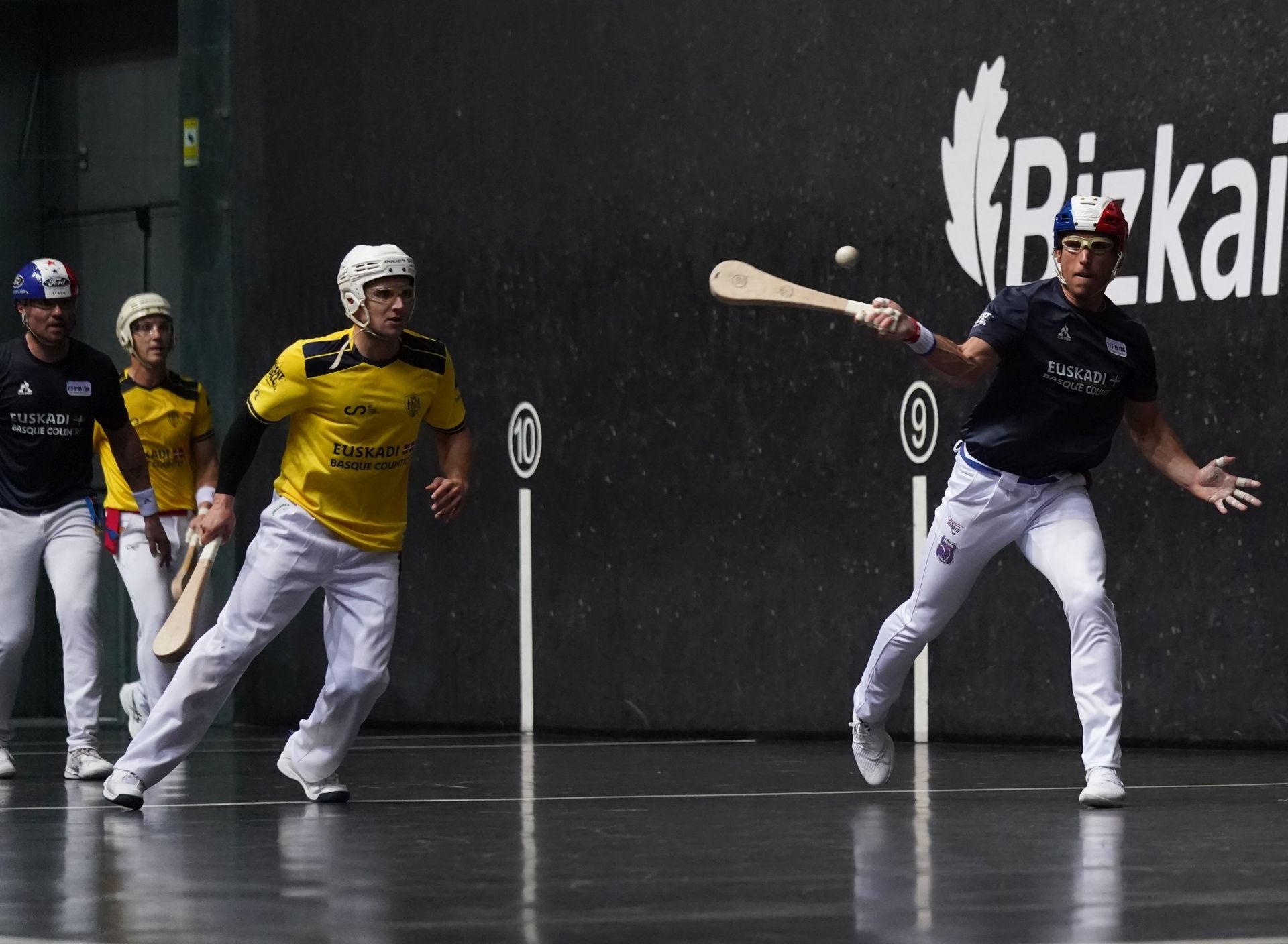 Necol golpea una pelota con la derecha ante la mirada del resto de pelotaris.