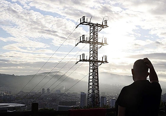 Una persona observa el cableado con el que red eléctrica transporta la energía sobre la ciudad de Bilbao