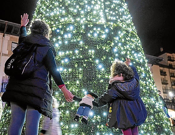 Una madre celebra con su hija el encendido del árbol de navidad instalado en Foru plaza de Gernika.