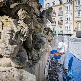 Un especialista limpia una pintada en la base del monumento.